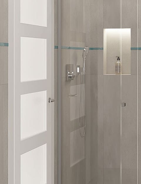 A modern bathroom featuring grey large-format wall tiles, a glass shower partition, wall-mounted toilet, and recessed lighting.