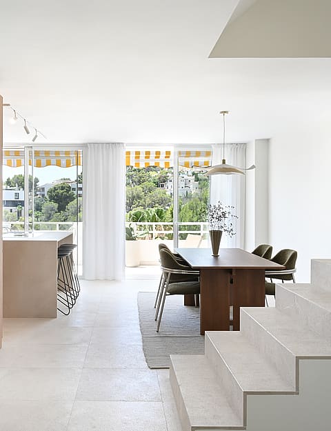 Living room with linen sofa, walnut coffee table, and floor-to-ceiling glazing framing seaview terrace