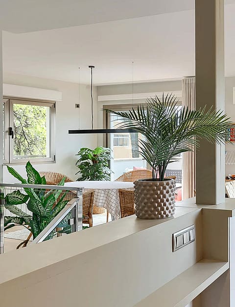 Interior view of an open-plan living room with a neutral sofa, patterned rug, open shelving, and natural light.
