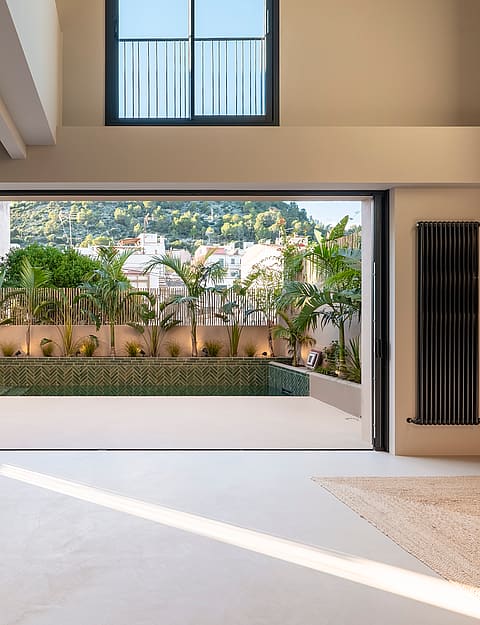 Open-plan living space featuring full-width sliding doors that lead to a private terrace with a pool and mountain views.