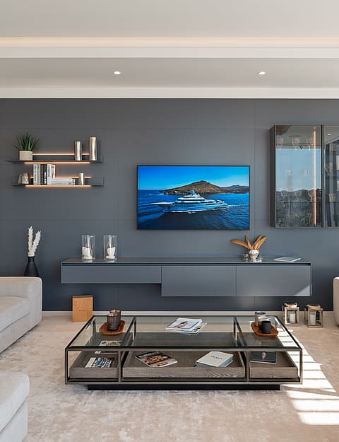 Symmetrical living area featuring a central charcoal media wall, floating grey console, and two beige sofas facing each other.