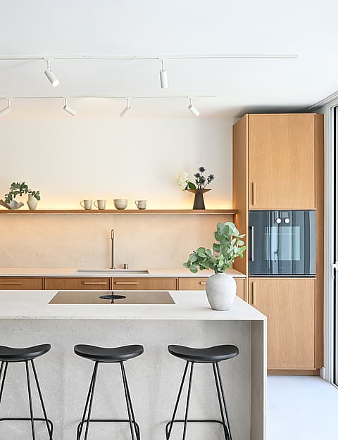 Open-plan kitchen in oak and Binissalem marble with sculptural concrete staircase and Zarci stone floors