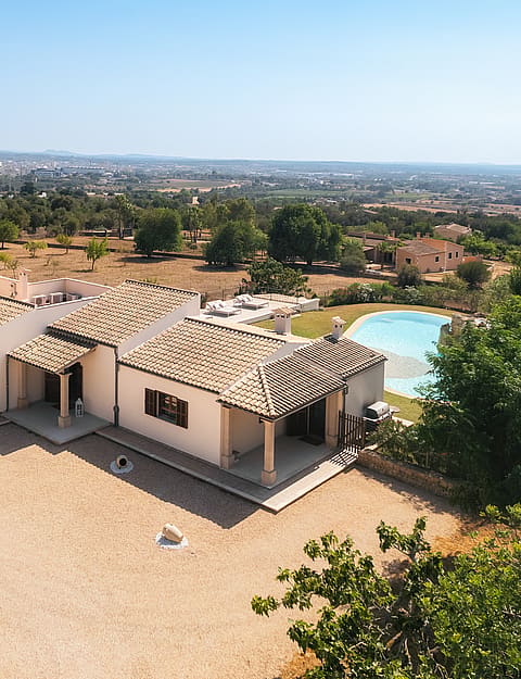 Vista aérea de una finca tradicional en Manacor con tejado de teja, jardín y piscina frente a la montaña.