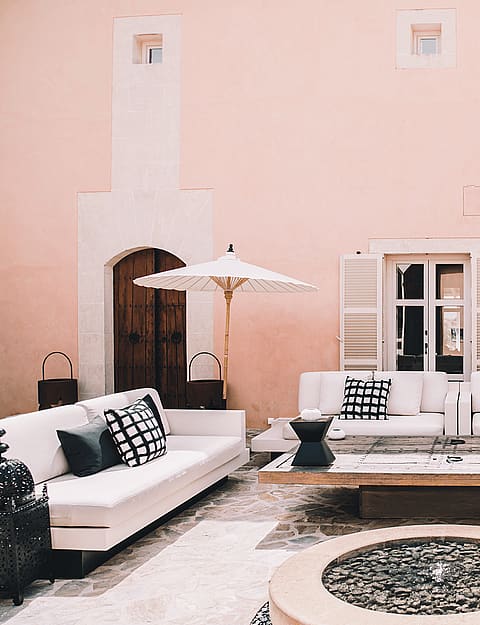 Outdoor courtyard of a Finca with pink plaster walls, white sofas, and stone flooring.