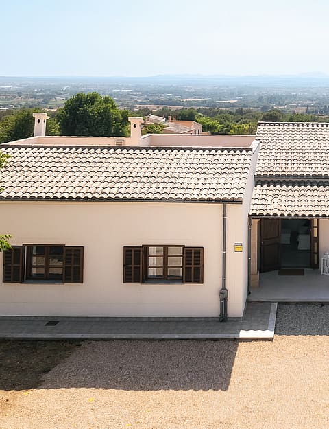 Vista exterior de una finca tradicional de una planta con muros encalados, tejado de teja y contraventanas de madera.