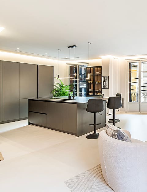 Modern open-plan living space with a dark island kitchen, textured white seating, and high ceilings in an Old Town apartment.