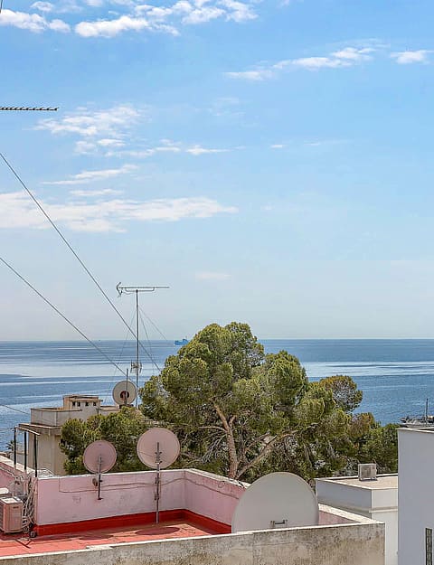 Elevated view overlooking the San Agustin coastline and Mediterranean sea under a clear blue sky with urban rooftops below.
