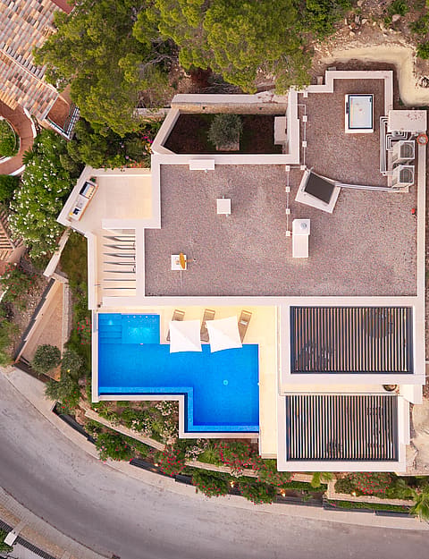 Top-down aerial view of a villa in Port d'Andratx showing a blue rectangular swimming pool, a flat roof, and surrounding vegetation.