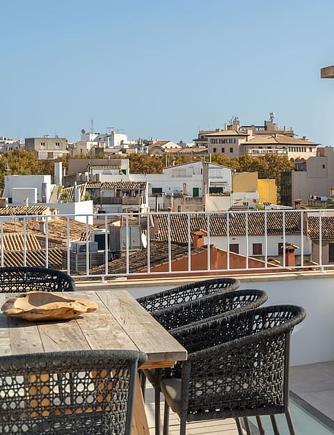 Rooftop terrace with wooden dining table and panoramic views of Palma Cathedral and the historic Old Town skyline.