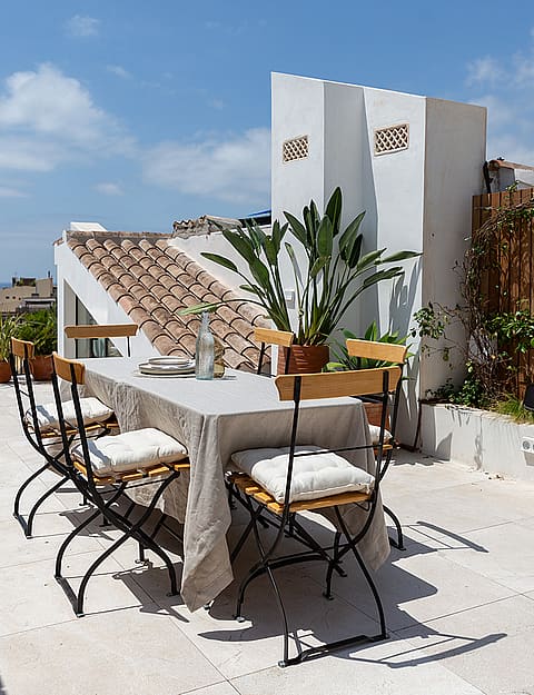 Rooftop terrace featuring an outdoor dining table, potted greenery, and views towards the Santa Eulàlia Church tower.