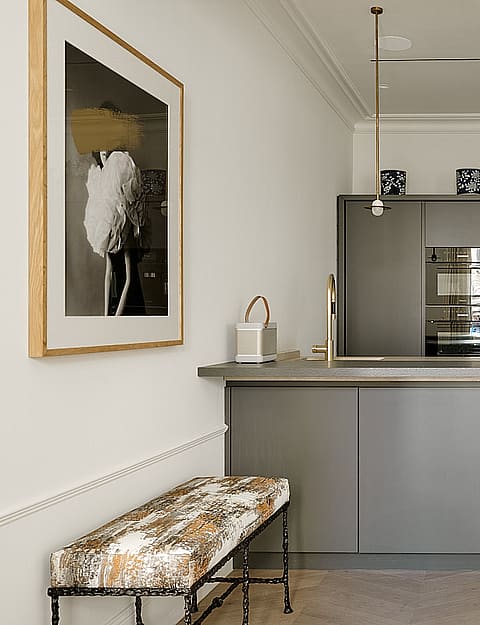 Contemporary kitchen featuring grey-toned cabinetry, professional-grade stainless steel appliances, white countertop, and brass pendant lights