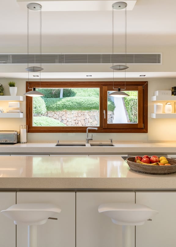 Fully fitted kitchen with white cabinetry, stone worktops, central island, Miele ovens and garden window