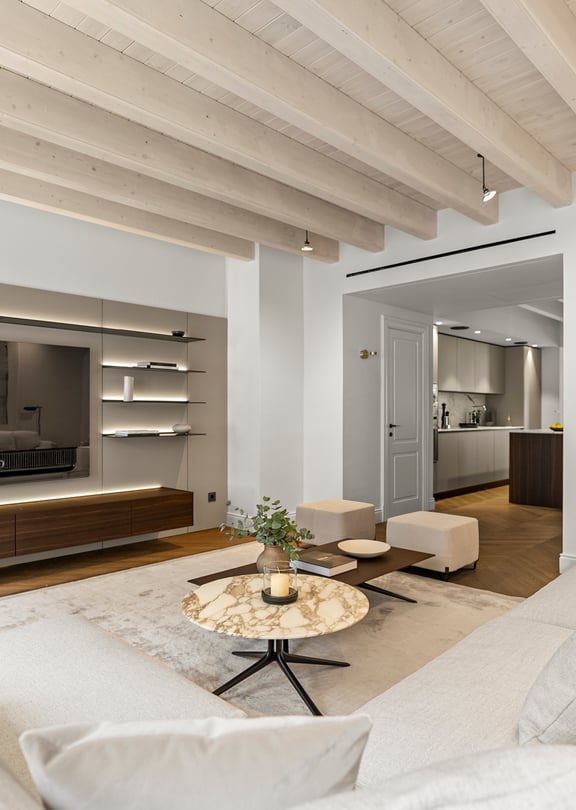 Contemporary living room featuring whitewashed ceiling beams, integrated backlit shelving, and a marble coffee table.