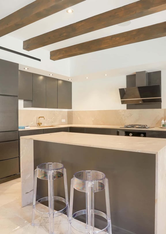Modern kitchen with dark grey cabinetry, central stone island, and exposed timber ceiling beams in an Old Town townhouse.
