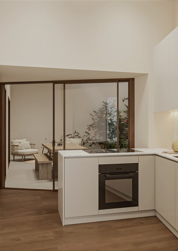 Compact kitchen with pale handleless cabinetry, marble splashback, brass tap, induction hob and integrated oven, glazed sliding partition to the living area.