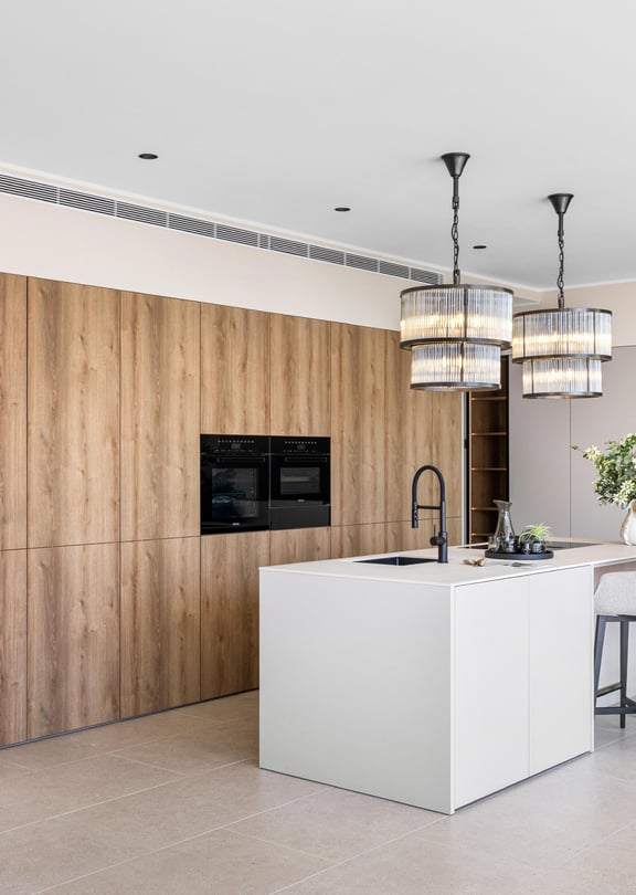 Fitted kitchen with full-height oak cabinetry, white composite island and two black-frame pendant lights