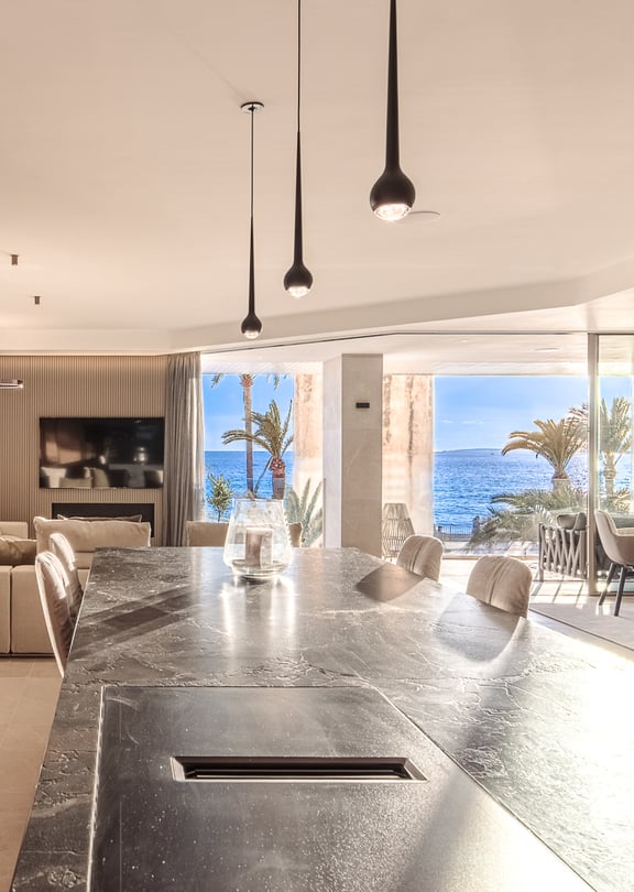 Dining area with marble countertops, designer pendant fixtures and seamless access to the waterfront loggia