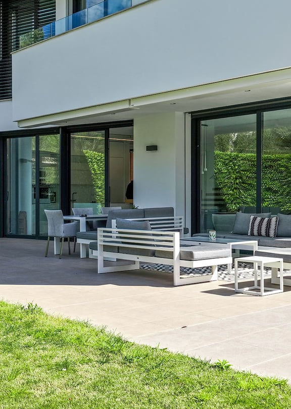 Rear of the villa with covered terrace, outdoor lounge seating and landscaped lawn.