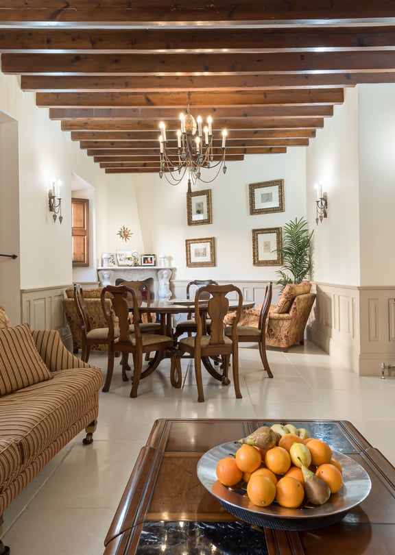Living and dining area with striped sofa, wooden dining table and beamed ceiling