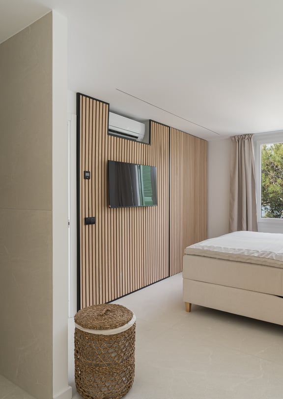 Contemporary bedroom featuring a vertical wood slat wall, upholstered bed, glass pendant lights, and garden views.