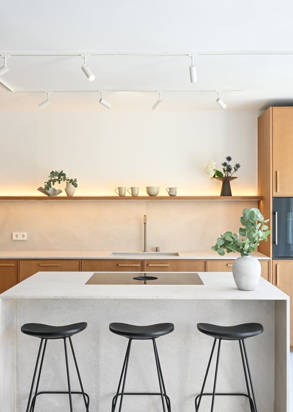 Open-plan kitchen in oak and Binissalem marble with sculptural concrete staircase and Zarci stone floors