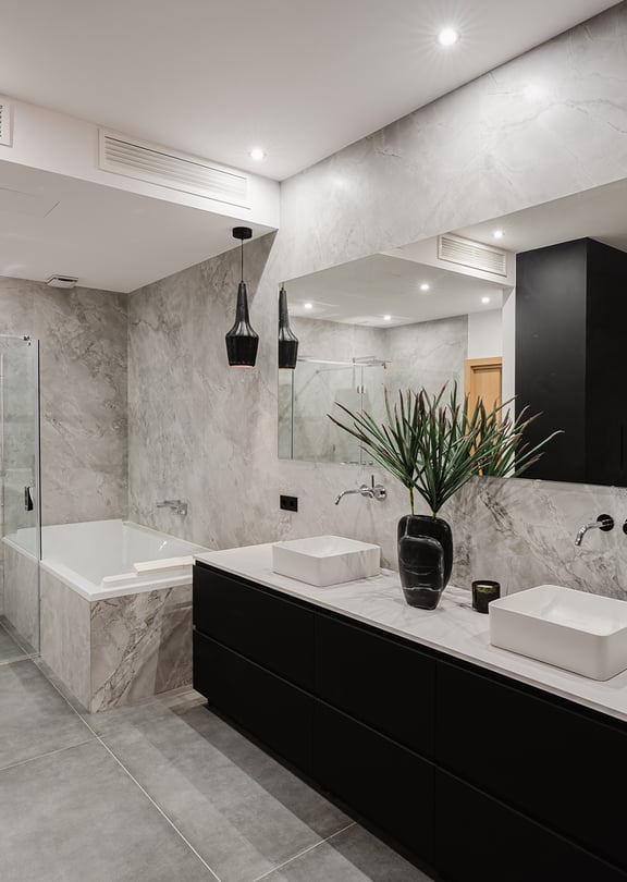 Modern bathroom featuring gray marble walls, a black floating vanity with double sinks, and a glass-enclosed walk-in shower.