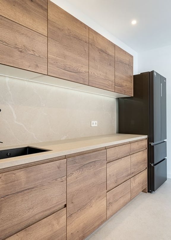 A modern kitchen in a townhouse features horizontal wood-grain cabinets, a matte black faucet, and a stone backsplash.