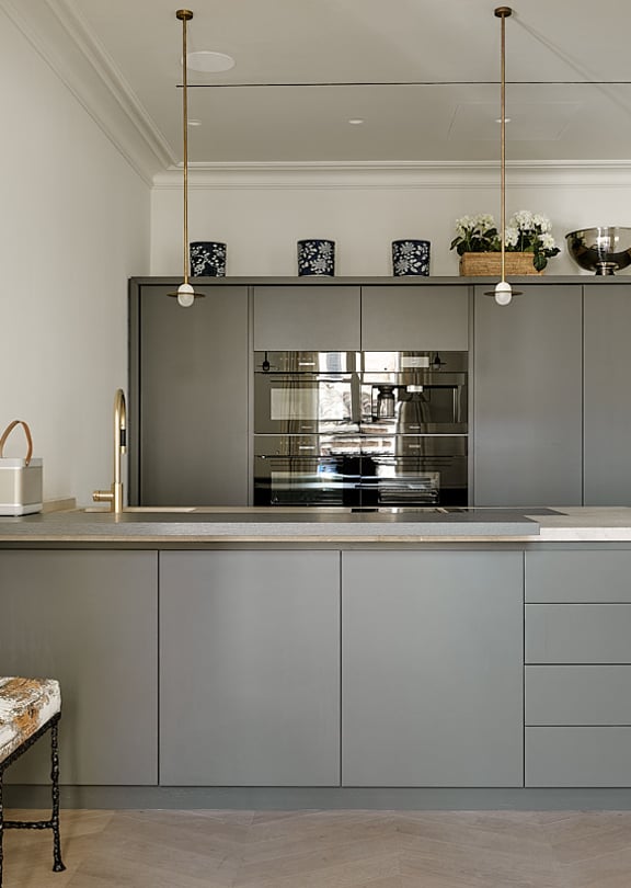 Contemporary kitchen featuring grey-toned cabinetry, professional-grade stainless steel appliances, white countertop, and brass pendant lights