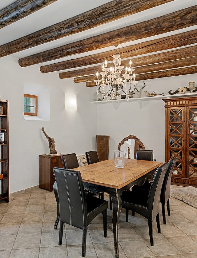 Rustic dining room with exposed wooden ceiling beams and terracotta floor tiles