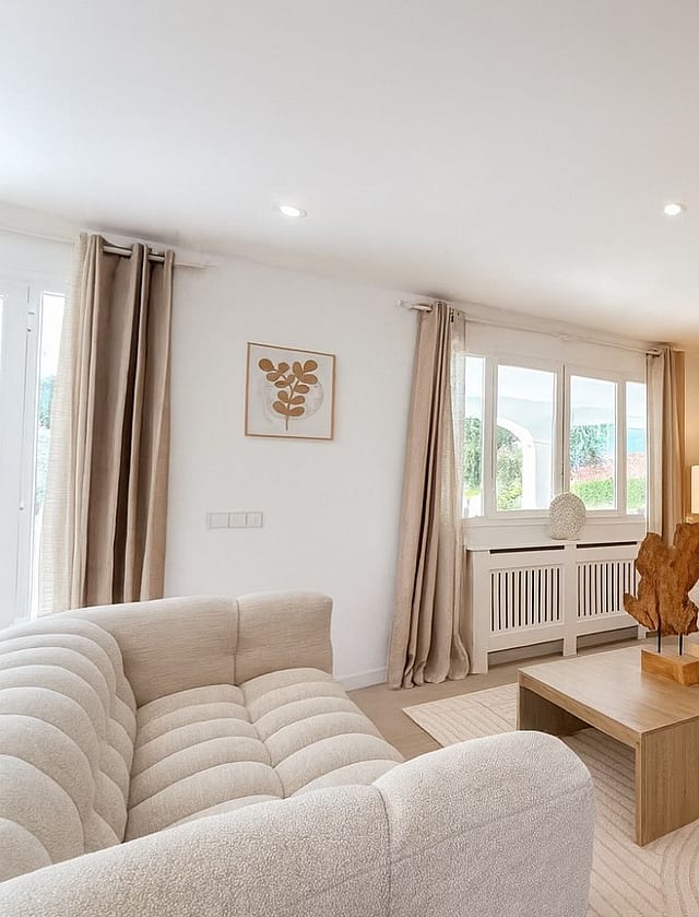 Living room with two cream bouclé sofas, wooden slat feature wall, low oak coffee table and tiled flooring