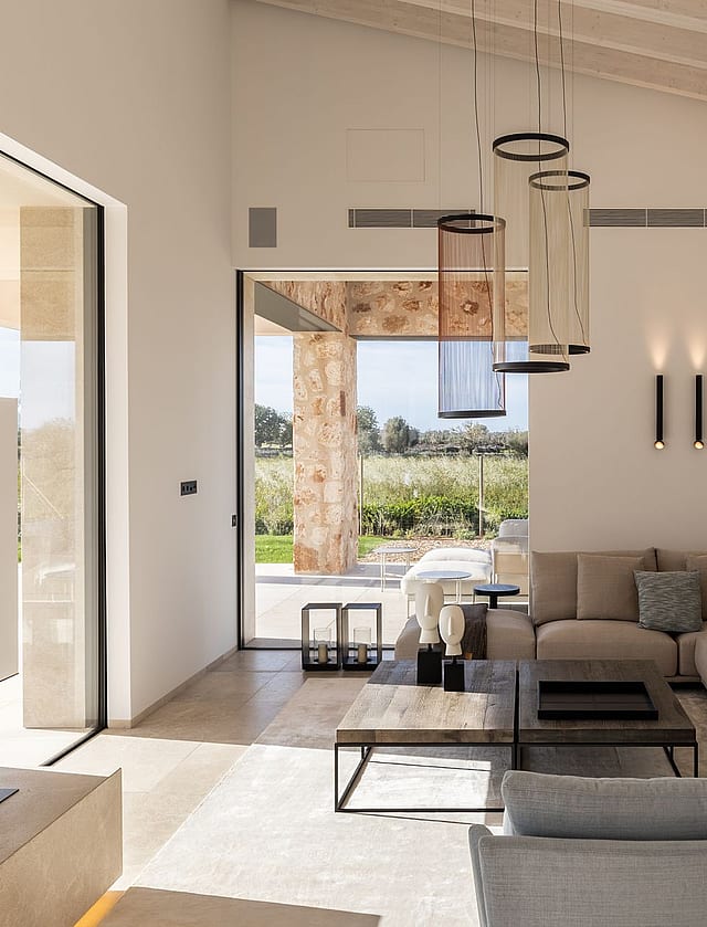 Living room with high vaulted ceiling, neutral sofa, and large glass doors opening to a terrace with mountain views.
