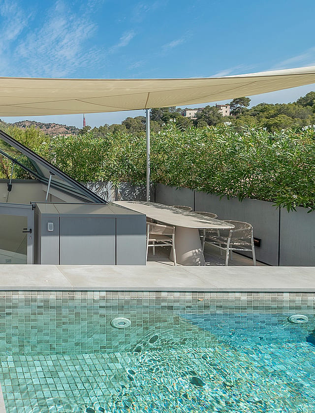 Rooftop terrace featuring a tiled swimming pool, modular beige sofa, dining area, and a beige shade canopy under clear skies.