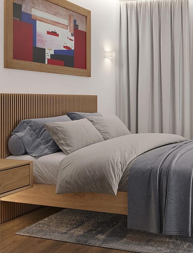 A modern bedroom featuring a light oak bed frame with a vertical-slatted headboard, soft grey textiles, a textured rug, and a wall-mounted nightstand under a framed print.