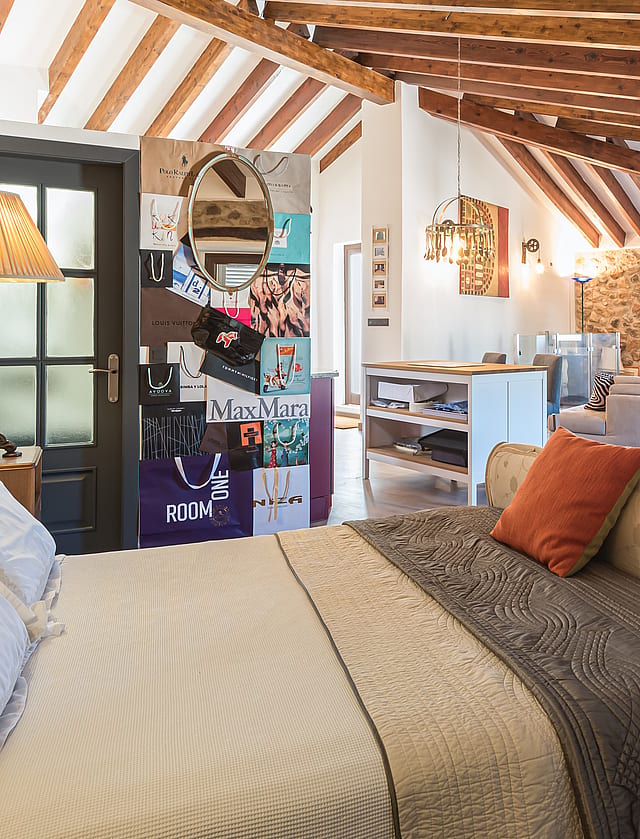 Loft-style bedroom featuring exposed wooden beams, stone walls, and an integrated living space.