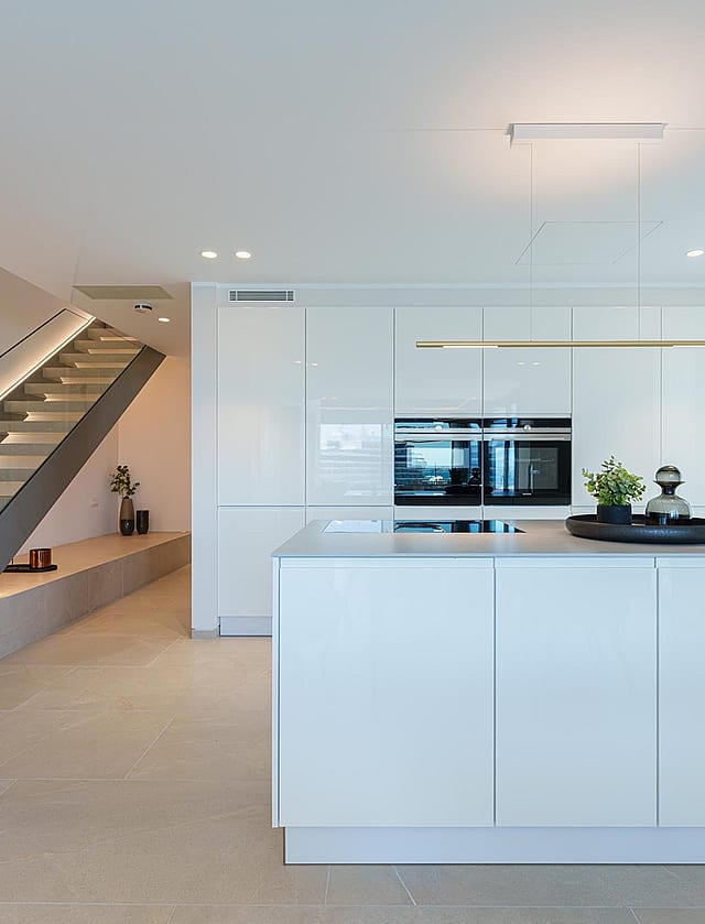 Cocina blanca moderna con isla y escalera abierta con iluminación LED integrada en un piso luminoso.