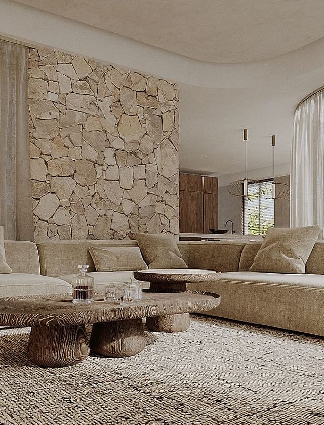 Modern living room with a large beige sectional sofa, a carved wood coffee table, and a feature wall made of round stone logs.