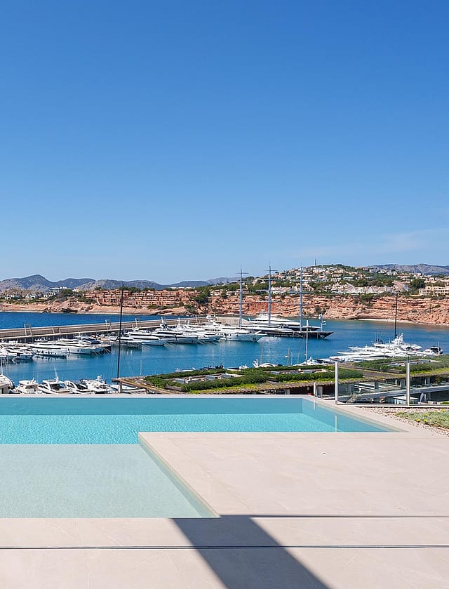 A rectangular infinity pool with turquoise water in the foreground, framing a direct view of the marina and yachts.