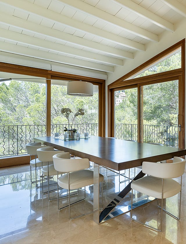 Large open-plan reception room with white beam ceilings, marble floors and art-hung wall leading to dining area