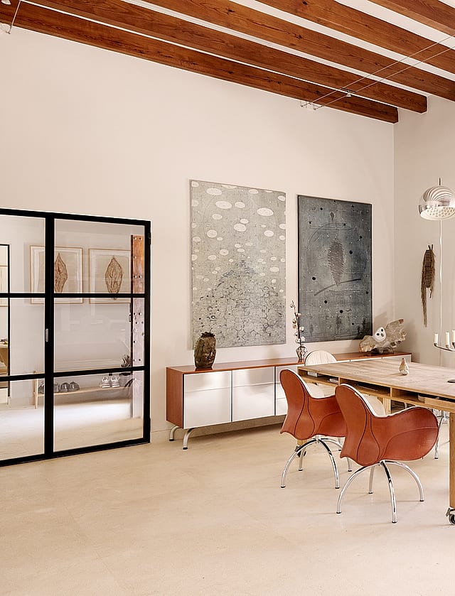 Dining room in a Finca featuring a long wooden table, leather swivel chairs, exposed ceiling beams, and a terrace doorway.
