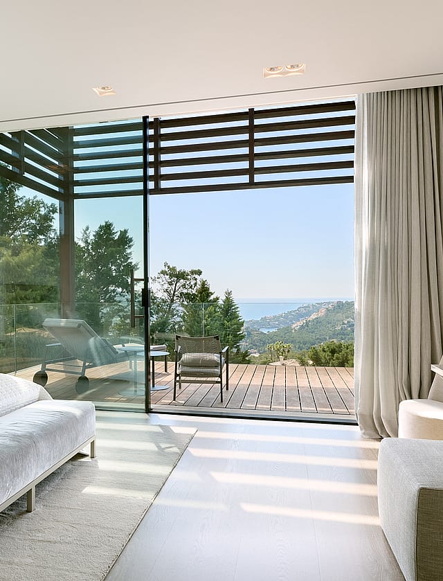 Bedroom with floor-to-ceiling glazing opening to a terrace over the sea and harbour