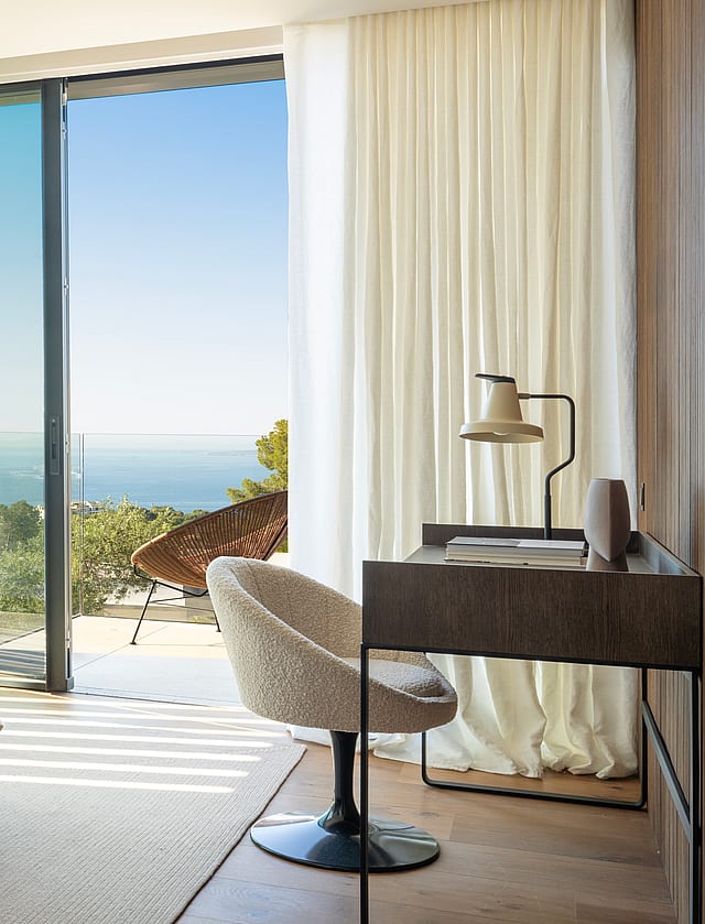 Master bedroom featuring a double bed, modern desk, and floor-to-ceiling windows overlooking the sea.
