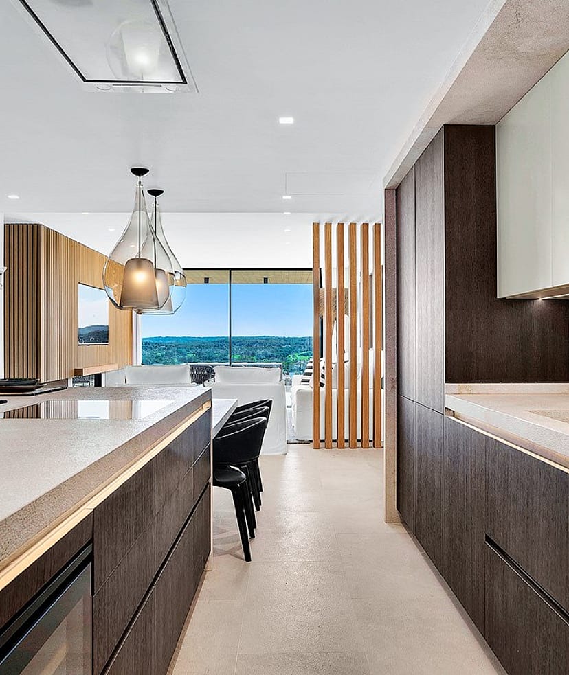 Modern kitchen with dark wood cabinetry, a stone kitchen island, and a clear view towards mountain scenery in Santa Ponsa.