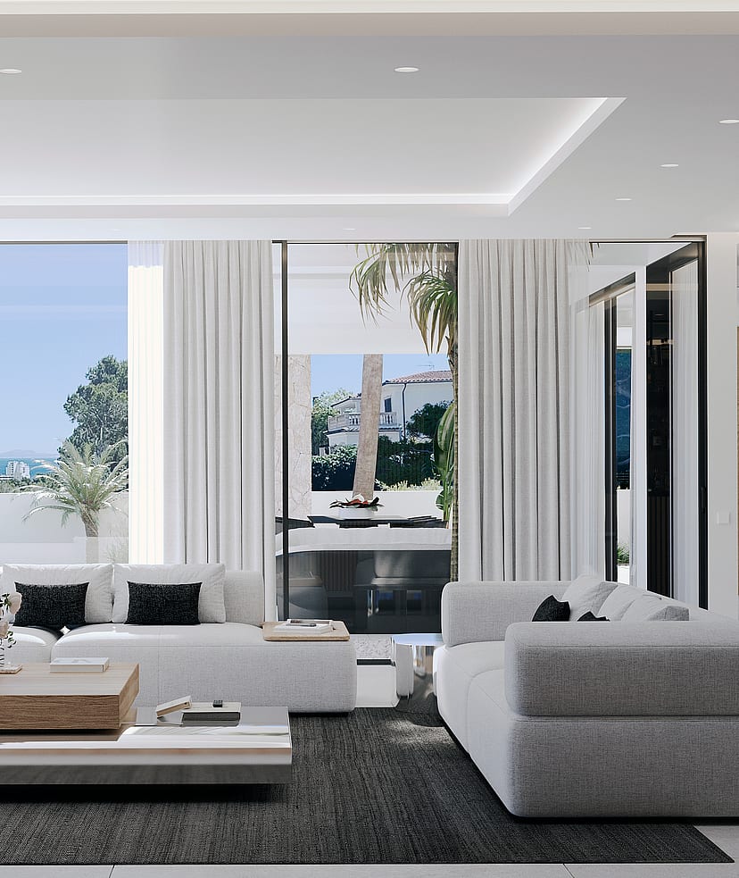 Modern open living room featuring white sofas, a light wood coffee table, dark area rug, and floor-to-ceiling sliding glass doors opening to a covered terrace with coastal views.