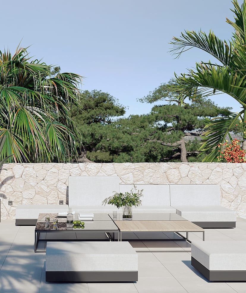 A contemporary outdoor terrace featuring low-profile modular white sofa seating and wooden coffee tables against a natural stone wall.