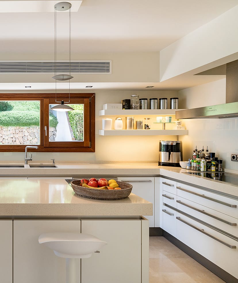 Fully fitted kitchen with white cabinetry, stone worktops, central island, Miele ovens and garden window