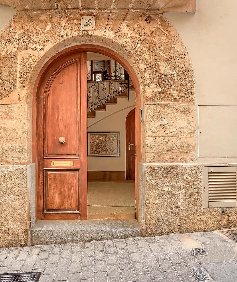 An arched timber front door set within a traditional natural stone facade on a cobblestone Old Town street.
