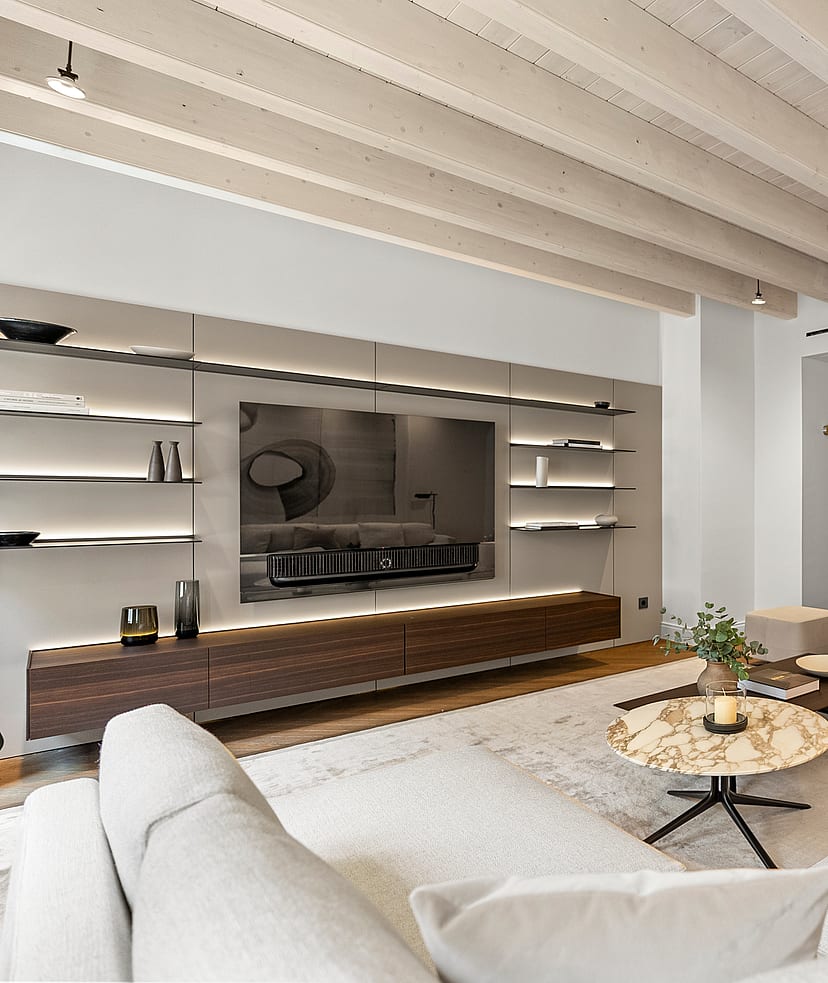 Contemporary living room featuring whitewashed ceiling beams, integrated backlit shelving, and a marble coffee table.
