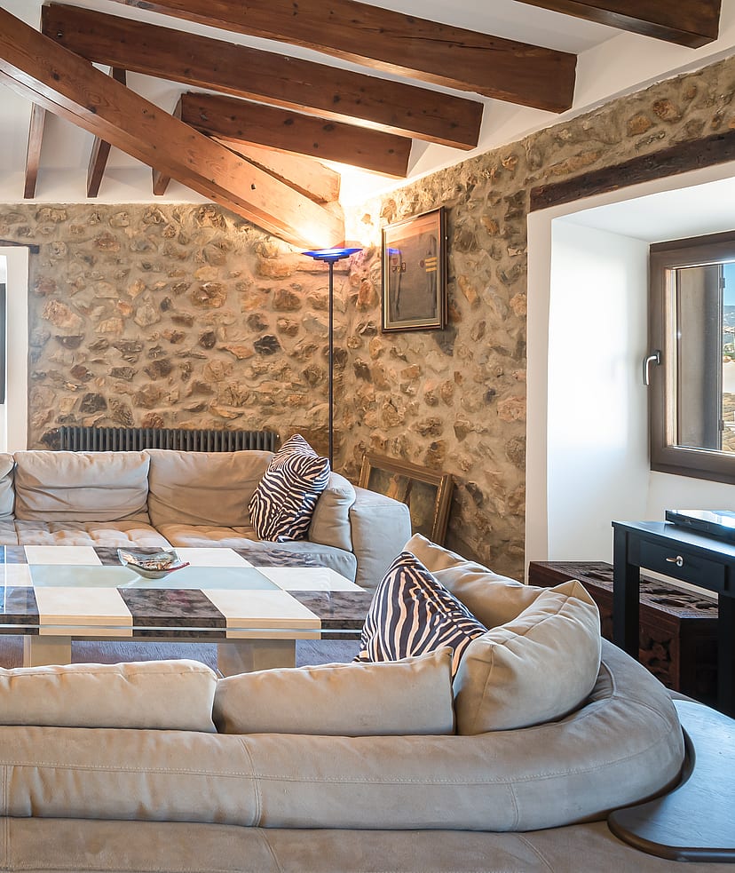 Living room with vaulted wood-beamed ceiling, stone feature wall and sectional sofa