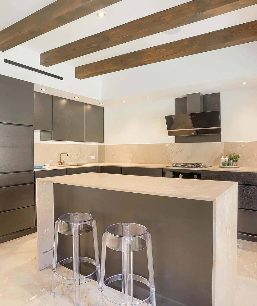 Modern kitchen with dark grey cabinetry, central stone island, and exposed timber ceiling beams in an Old Town townhouse.
