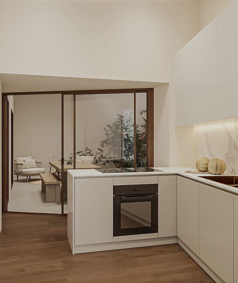 Compact kitchen with pale handleless cabinetry, marble splashback, brass tap, induction hob and integrated oven, glazed sliding partition to the living area.